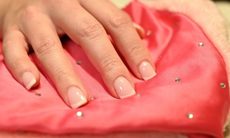 prikaz ruke sa francuskim manikirom na roze sunđerčiću